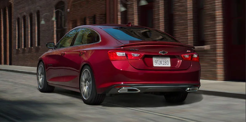 A red Chevy Malibu driving down the road.